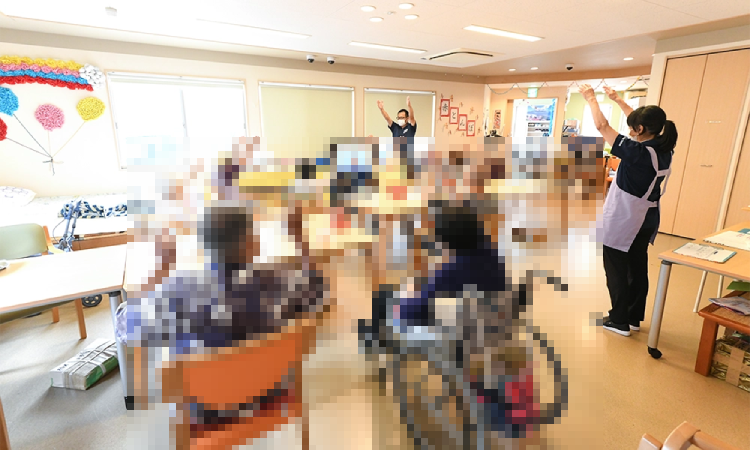 ご利用者様と職員がテレビの前で体操している様子